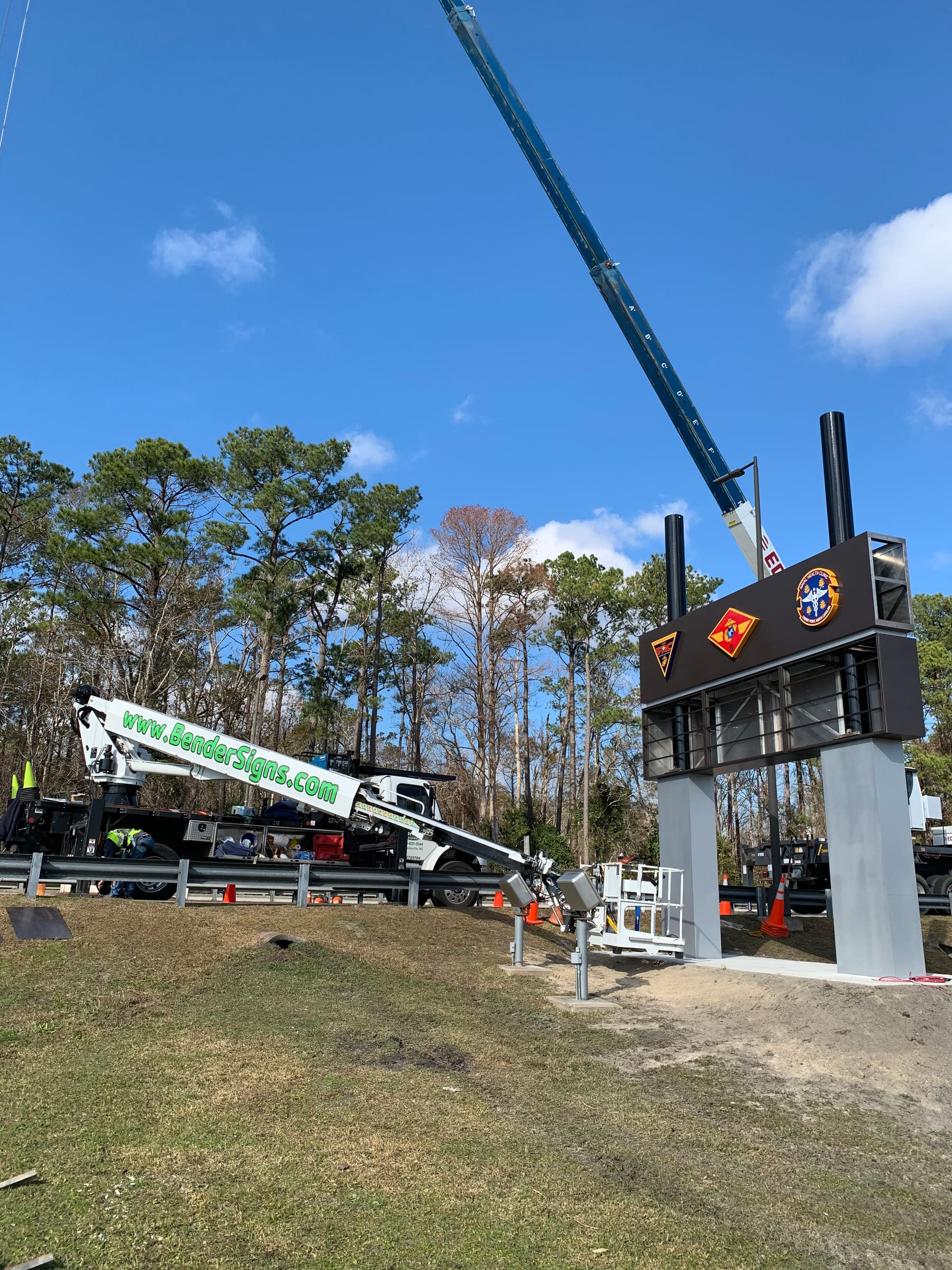 Large crane and Bender Signs boom truck erecting a sign structure at MCCS Cherry Point